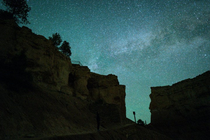 Silhouette of canyon walls under a starry night sky with visible Milky Way.